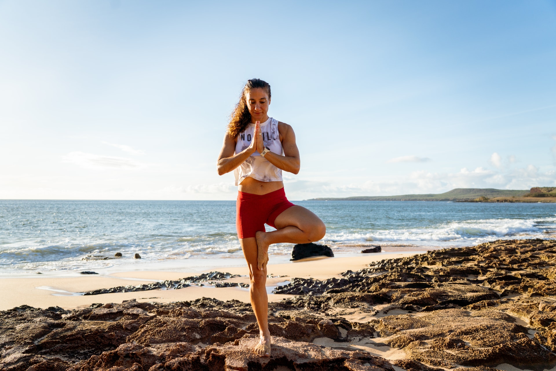Athlete balancing in a yoga pose on the beach